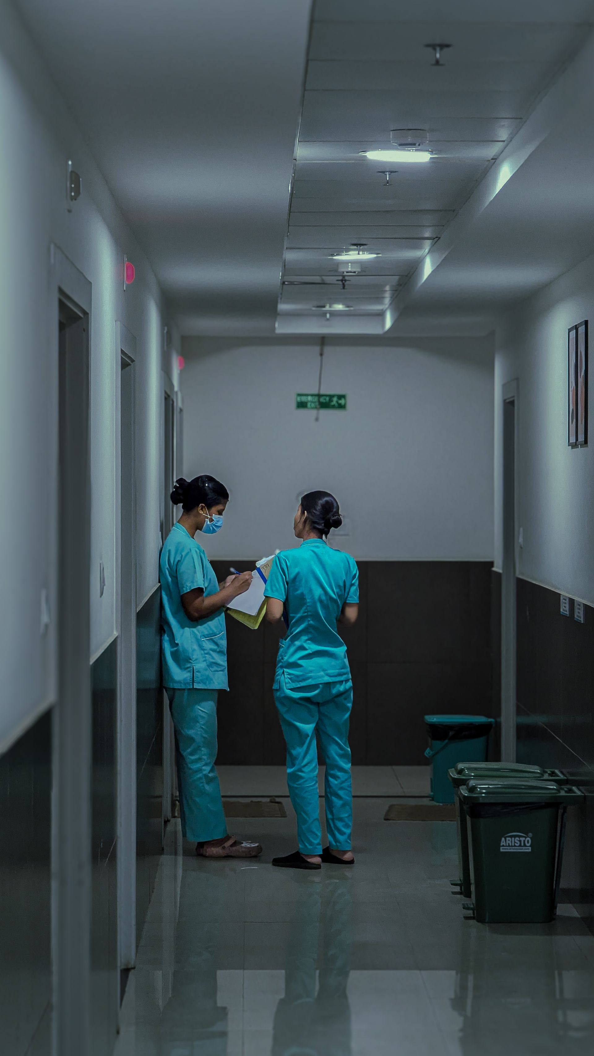 Two nurses reviewing patient notes in a hospital corridor